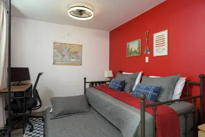 a bedroom with a bed and a red wall at Cozy Family Retreat with Yard - Walk to Olde Town in Arvada