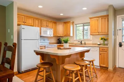 a kitchen with a white refrigerator and wooden cabinets at Ski Town Hideaway | Fireplace + Walk to Downtown in Winter Park