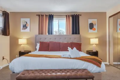 a bedroom with a large bed with a bench and two lamps at 6BD Near DT - BBQ Grill, Games & Football Fun in Arvada