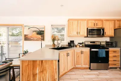 a kitchen with wooden cabinets and a black appliances at Ralston Creek Cottage - Serene Park Views in Arvada