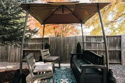 a patio with a bench and chairs under an umbrella at Ralston Creek Cottage - Serene Park Views in Arvada