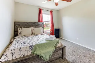 a bedroom with a bed and a window with red curtains at Fenced-In Yard with Deck Pet-Friendly Lochbuie Home