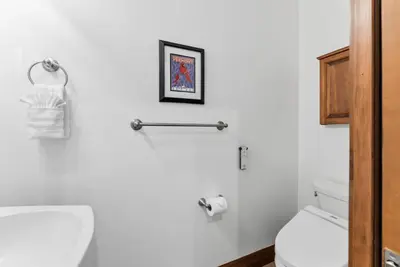 a white bathroom with a toilet and a picture on the wall at Breckenridge Stay Hot Tub Walk to Trails in Breckenridge