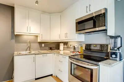 a kitchen with white cabinets and stainless steel appliances at Furnished Patio! Suburban Gem 11 Mi to Dtwn Denver in Arvada