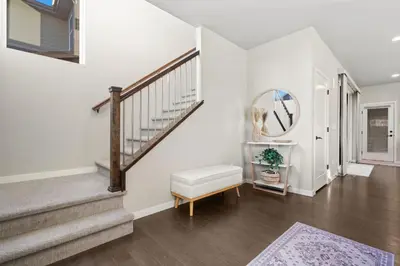 a living room with stairs and a mirror at Comet Haus Modern 3BR with Office and King Beds in Fort Collins