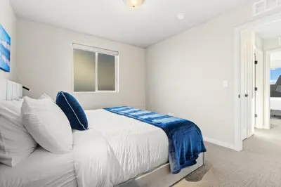 a white bedroom with a bed with blue pillows at Comet Haus Modern 3BR with Office and King Beds in Fort Collins