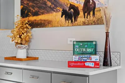a table with books and a painting on the wall at Comet Haus Modern 3BR with Office and King Beds in Fort Collins