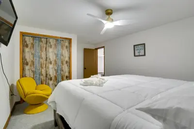 a bedroom with a white bed and a yellow chair at 6 Mi to Barr Lake Apt with Yard and Pool Access! in Brighton