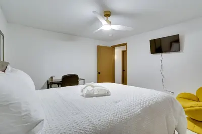 a bedroom with a white bed with a ceiling fan at 6 Mi to Barr Lake Apt with Yard and Pool Access! in Brighton