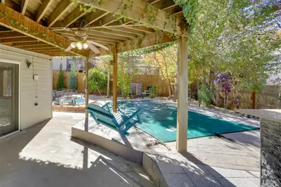 a swimming pool under a pergola with a blue chair at 6 Mi to Barr Lake Apt with Yard and Pool Access! in Brighton