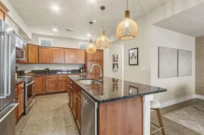 a kitchen with wooden cabinets and granite counter tops at Ember and Ash Designer Home with King Beds, Games in Fort Collins