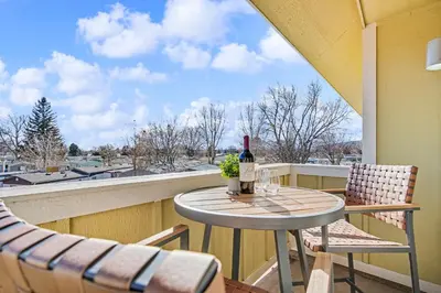 a table and chairs on a balcony with a bottle of wine at The Revive Loft with Balcony, Workspace and Bikes in Fort Collins