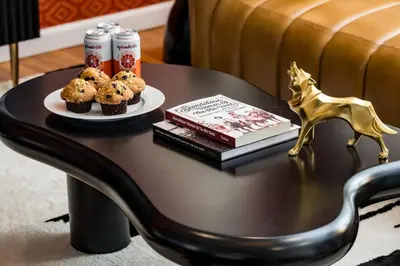 a coffee table with a plate of muffins and a book at The Wild Western - 5Bed, Hot Tub, Sauna, Mini Putt, Fire Pit in Denver