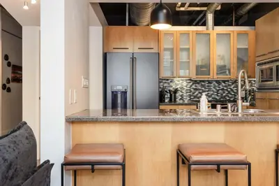 a kitchen with a refrigerator and two stools at a counter at Union Station downtown and gameday retreat! in Denver