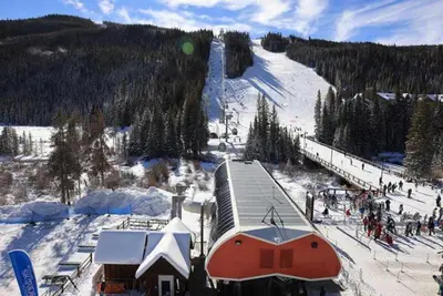a snow covered ski slope with a building and a ski lift at Kindred Resort Luxury Ski In, Ski Out 2 Bedroom Residence At The River Run Gondola in Dillon