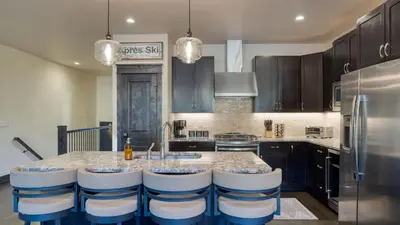 a kitchen with a sink and a counter with stools at Fireplace Game Room Mountain Views Near Golf Dining Keystone River Run by AvantStay in Dillon