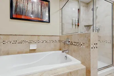 a white tub in a bathroom with a glass door at Base Camp One 403 in Granby