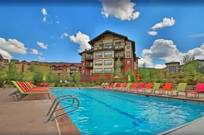 a hotel with a pool with chairs and a building at Base Camp One 316 in Granby