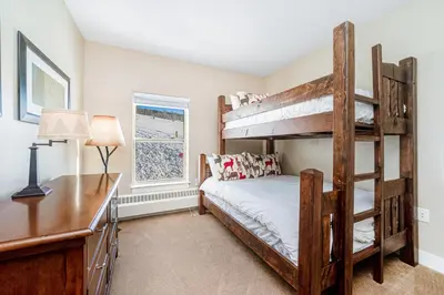 a bedroom with two bunk beds and a desk at Base Camp One 201 in Granby