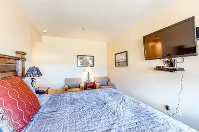 a bedroom with a bed and a flat screen tv at Base Camp One Penthouse 416C in Granby