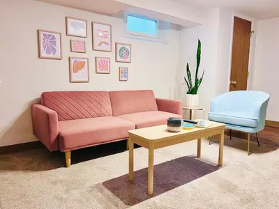 a living room with a pink couch and a table at Sloans Lake Basement Suite in Denver