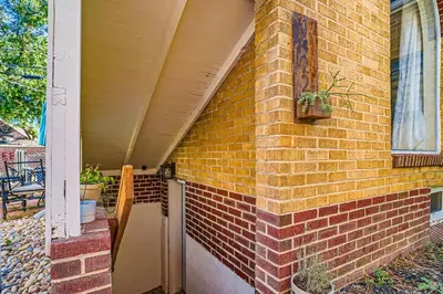a house with a brick wall with a porch at Sloans Lake Basement Suite in Denver