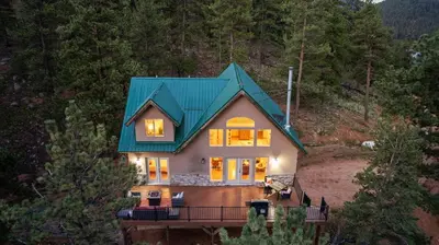 a house with a green roof on a hill at Mountain View Retreat- Private Hot Tub & Views in Bailey