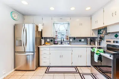 a kitchen with white cabinets and a stainless steel refrigerator at Walk to Old Town Lafayette! Cozy Couples Escape in Lafayette