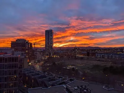 a sunset over a city with a tall building at Sunset View in Denver
