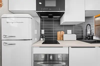 a kitchen with white cabinets and a white refrigerator at Downtown Denver Suite - Skyline Views in Denver