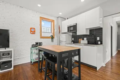 a kitchen with white cabinets and a wooden table at Downtown Denver Suite - Skyline Views in Denver