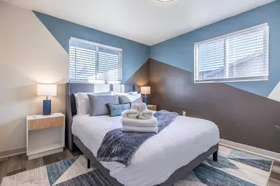 a bedroom with a bed with blue walls and two windows at Movie Theater Game Console Arcade Fire Pit BBQ in Westminster