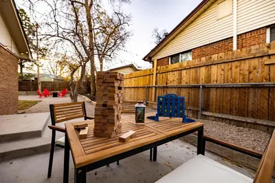 a wooden table with bricks on it next to a fence at Movie Theater Game Console Arcade Fire Pit BBQ in Westminster