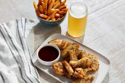 a plate of food with a bowl of fries and a glass of beer at Holiday Inn & Suites Commerce City - Denver Airport by IHG in Commerce City