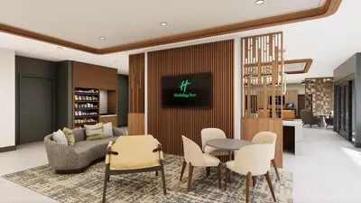 a living room with a couch and a table and chairs at Holiday Inn & Suites Commerce City - Denver Airport by IHG in Commerce City