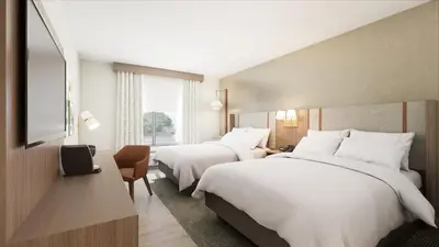a hotel room with two beds and a television at Holiday Inn & Suites Commerce City - Denver Airport by IHG in Commerce City