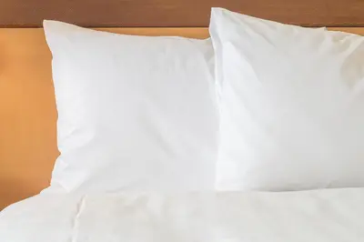 a bed with white sheets and pillows on it at Holiday Inn & Suites Commerce City - Denver Airport by IHG in Commerce City