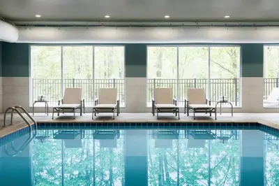 a pool in a hotel with chairs and tables and windows at Holiday Inn & Suites Commerce City - Denver Airport by IHG in Commerce City
