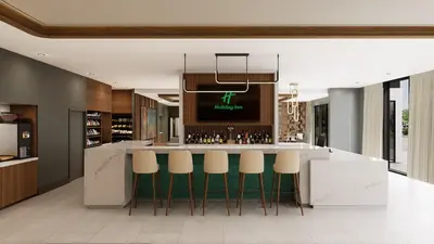 a kitchen with a bar with green stools at Holiday Inn & Suites Commerce City - Denver Airport by IHG in Commerce City