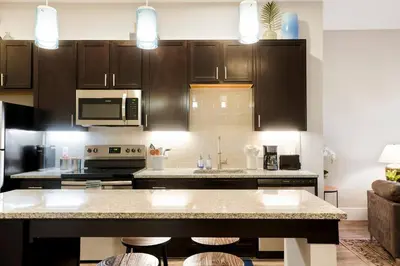 a kitchen with brown cabinets and a kitchen island with stools at Heart of Gold-en - Walk Everywhere -Close to Red Rocks in Golden