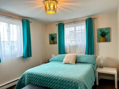 a bedroom with a green bed with blue curtains and a chandelier at Longmont board games, beds, and boats - 4BR in Longmont