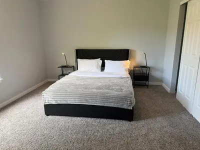 a bedroom with a bed with a black headboard and two tables at CENTRAL DENVER FAMILY HOMe in Denver