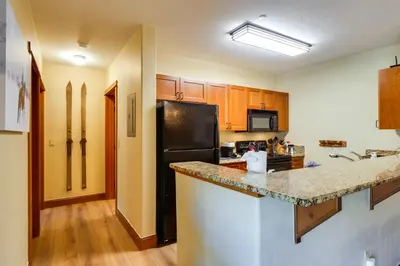 a kitchen with a black refrigerator and wooden cabinets at Family Ski Trip! Upscale Keystone Condo Near Lift in Dillon