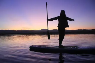 a woman standing on a paddle board in the water at Steps to Lake Mcintosh, Basement 1BR in Longmont