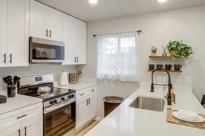 a kitchen with white cabinets and a sink at Modern and Pet-Friendly! Northern Colorado Retreat