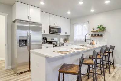 a kitchen with white cabinets and a stainless steel refrigerator at Modern and Pet-Friendly! Northern Colorado Retreat