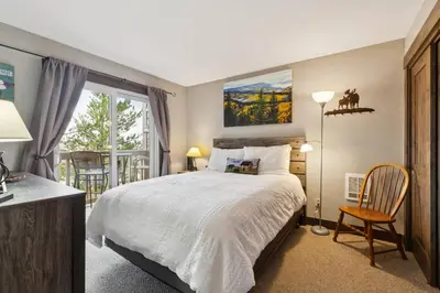 a bedroom with a bed and a chair and a window at Ski & Golf by Sweetheart Stays in Granby