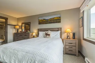a bedroom with a white bed with a dog on it at Ski & Golf by Sweetheart Stays in Granby