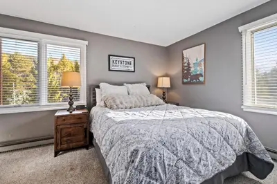 a bedroom with a bed and two windows at Key Condo Slopeside - Walk to Lifts, Pool/Hot Tub, Fantastic Views in Keystone