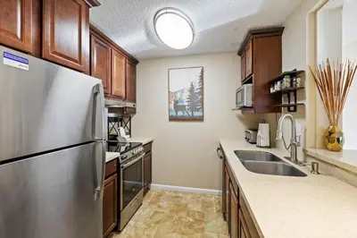 a kitchen with a stainless steel refrigerator and wooden cabinets at Key Condo Slopeside - Walk to Lifts, Pool/Hot Tub, Fantastic Views in Keystone